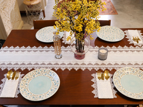 The Amélie Lace Table Runner by Uahan on a dining table set for four