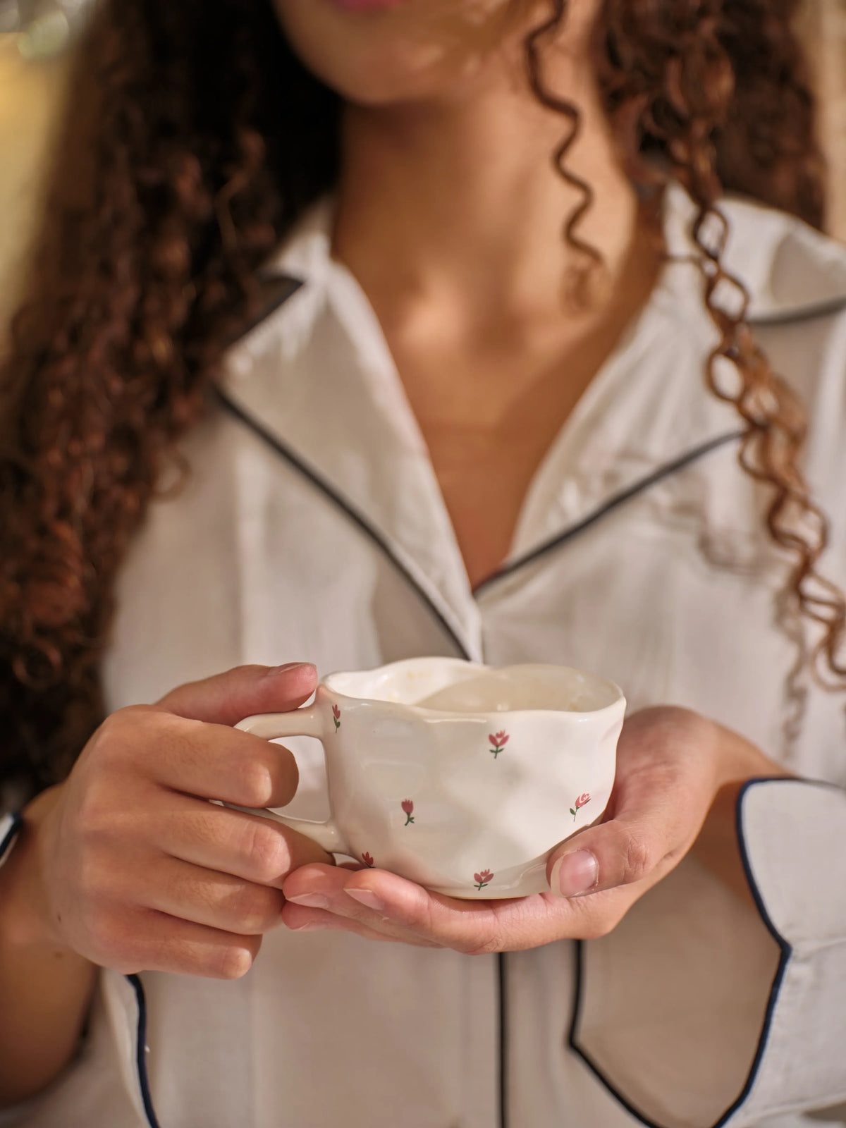 The Floral Tea Cup & Saucer by Uahan, held in both hands