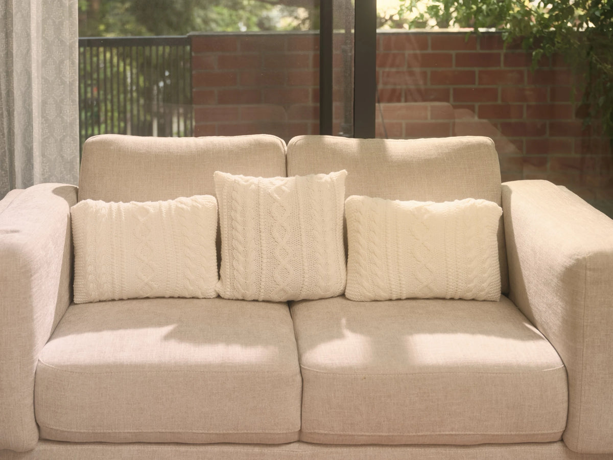 The Maman Cable-Knit Cushion Covers by Uahan — a trio on a linen sofa in morning light